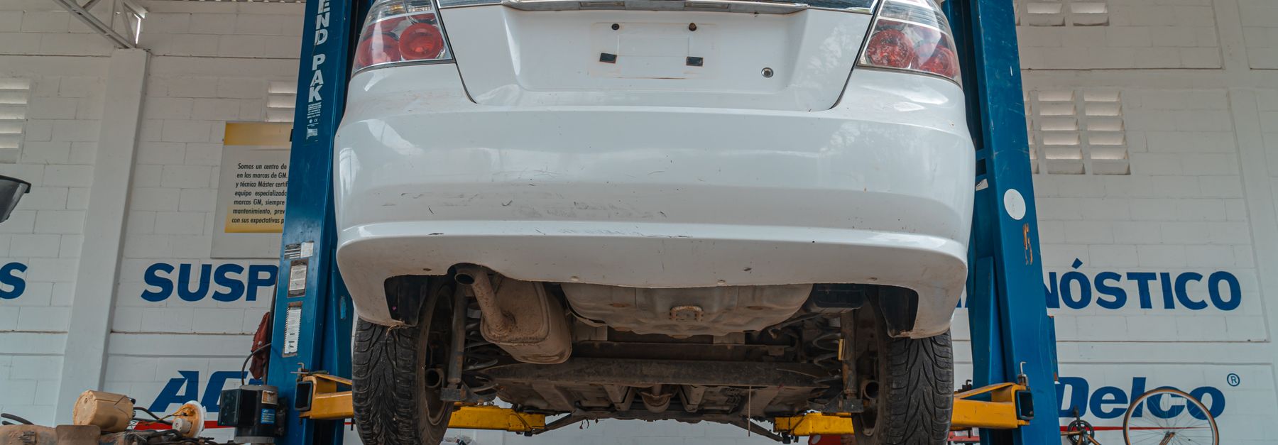 A white Chevrolet car is lifted for maintenance in an automotive repair shop.